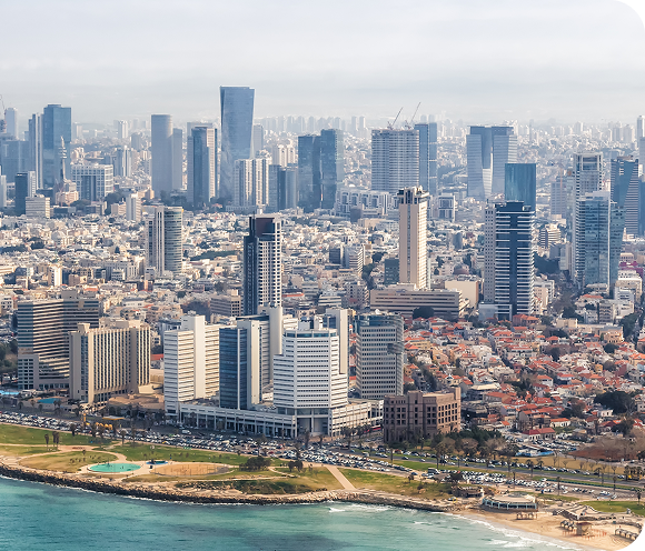 Aerial view of a coastal city with tall modern skyscrapers, mid-rise buildings, and residential areas. The shoreline features a beach, green park space, and a busy road—ideal for businesses like MSPs focused on CyberSecurity and innovation.